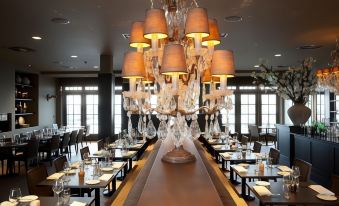 a large dining room with a long table and multiple chandeliers hanging from the ceiling at Fletcher Hotel - Restaurant Nautisch Kwartier