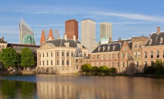 a large building with a clock tower is reflected in the water , surrounded by other buildings at The Collector