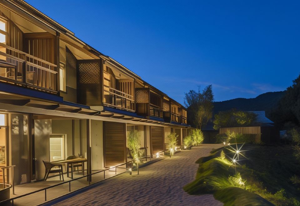 a modern wooden house with multiple balconies , lit up at night , surrounded by greenery and lit up at night at Okuhita Onsen Umehibiki