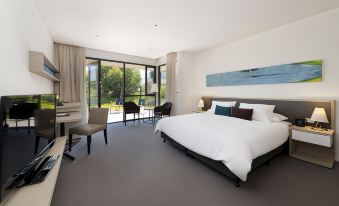 a spacious bedroom with a large bed , a dining table , and a window overlooking a garden at Flinders Hotel