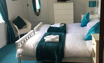 a bedroom with a white bed , green curtains , and a tv on the wall , along with a dresser and a mirror at Fox House Thirdpart Farm