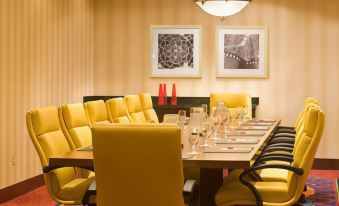 a conference room with yellow chairs arranged in a long table , surrounded by framed art on the walls at Marriott Saddle Brook