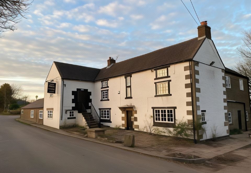 a large white house with a black and white striped chimney is situated on a street corner at The Bear Inn