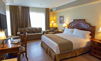 a hotel room with a large bed , two chairs , and a desk , all in a well - lit setting at Hotel Brossard