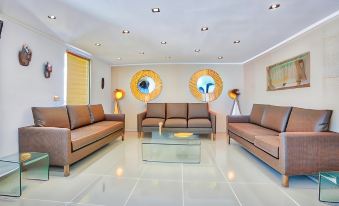 a modern living room with brown couches , a glass coffee table , and two round mirrors on the wall at Happy Days