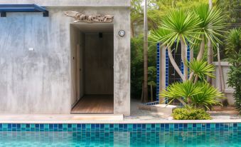 a modern house with an open door leading into a pool , surrounded by greenery and trees at B2 Sriracha Premier Hotel