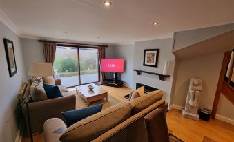 a living room with a large flat - screen tv mounted on the wall , a couch , and a chair at Hustyns Resort Cornwall