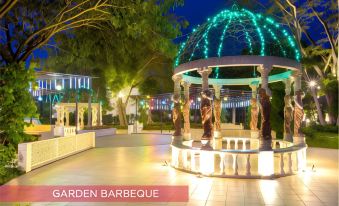 a large , well - lit gazebo with a stone fountain in the center , surrounded by a park - like setting at Ramada Suites by Wyndham Solo