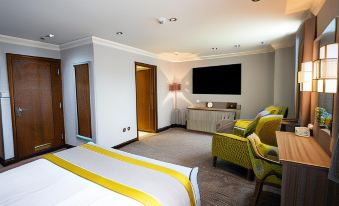 a hotel room with a comfortable bed , a flat - screen tv , and a comfortable seating area at Best Western Plus Pastures Hotel