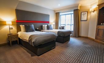 a hotel room with two beds , one on the left and one on the right side of the room at Villiers Hotel