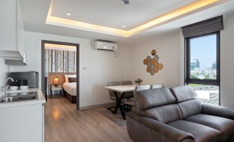 The bedroom features a spacious open concept design, incorporating a living room area with a couch, table, and bed at Orion Hotel & Residence Bangna