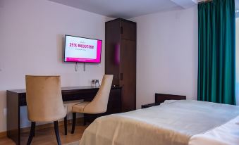 a hotel room with a comfortable bed , a desk , and a tv mounted on the wall at Hotel THR Center