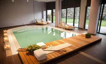 a large indoor swimming pool surrounded by lounge chairs , with lounge chairs and towels placed around the pool at Winter Garden Hotel Bergamo Airport