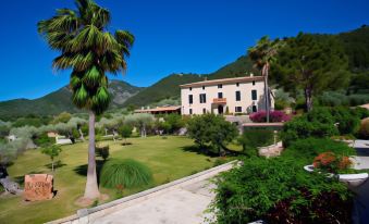 a large house with a palm tree in front of it and mountains in the background at Monnaber NOU Finca Hotel & Spa