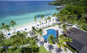 a beautiful beach resort with a large pool surrounded by palm trees and a sandy beach at Palau Hotel