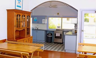 a kitchen with blue cabinets , a dining table , and a microwave , as well as a living room area with wooden furniture at Waterview Gosford Motor Inn