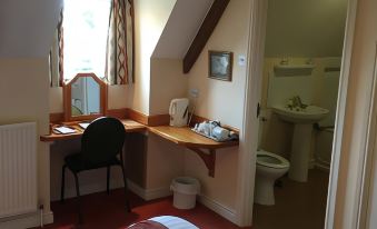 a bedroom with a bed , desk , and chair , as well as an open doorway leading to a bathroom at Malt House