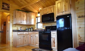 a cozy kitchen with wooden cabinets , black appliances , and a rug on the floor near the stove at Wilderness Presidential Resort