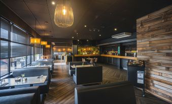 a modern restaurant with black leather booths , wooden tables , and chandeliers , creating a cozy atmosphere at Hotel Launceston
