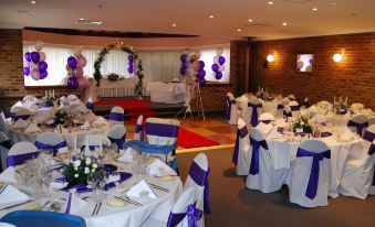 a well - decorated banquet hall with multiple tables set up for a formal event , including white tablecloths , blue napkins , and at Abcot Inn