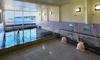an indoor swimming pool with a large window overlooking the ocean , providing a view of the water at Hakugei