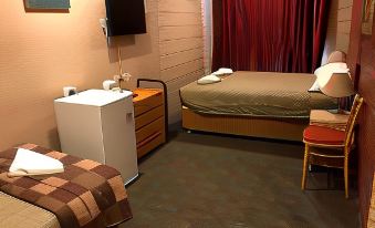 a hotel room with two beds , a chair , and a desk , along with a tv and other amenities at Cottonwood Lodge