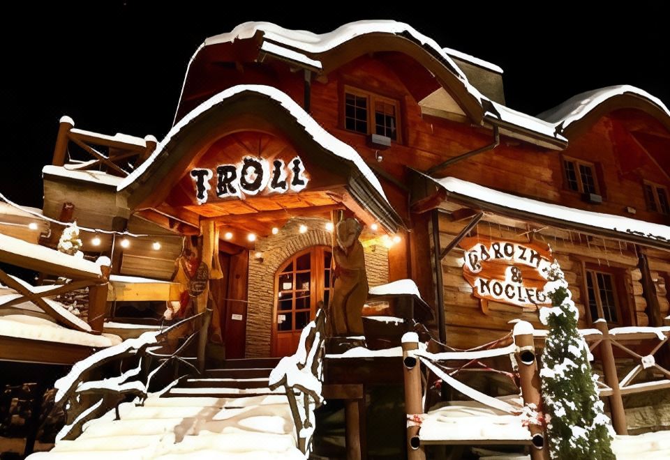 "a snow - covered building with a sign that reads "" troll "" in front of it , surrounded by trees" at Troll