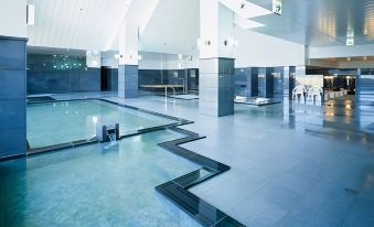 a large indoor swimming pool with a glass ceiling , allowing natural light to fill the space at Furano la Terre