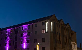 "a large building with purple lights and a sign that says "" hotel "" is lit up at night" at Premier Inn Penzance