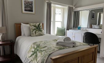 a well - decorated bedroom with a large bed , wooden furniture , and a white comforter , along with a window and desk at Lovelady Shield Country House Hotel