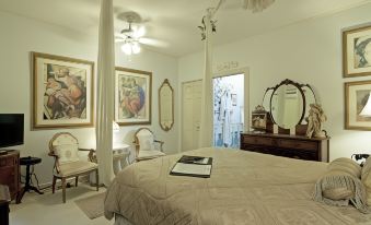a large bedroom with a white bed , multiple paintings on the wall , and a chandelier at Sabal Palm House Bed and Breakfast