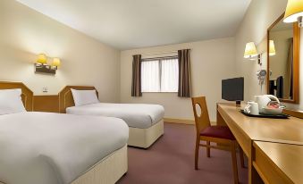 a hotel room with two beds , a desk , and a window , giving it a cozy and comfortable atmosphere at Days Inn by Wyndham Sutton Scotney South