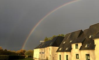 a house with a rainbow in the sky , and the house is being darkened by rain at Best Western Armor Park Dinan