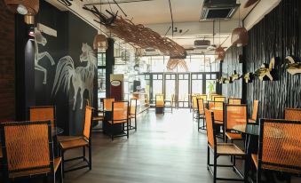 a dining area with wooden chairs and tables , along with a mural on the wall at The Happy 8 Retreat @ Kuala Sepetang