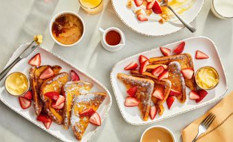 a dining table with a variety of food items , including french toast , strawberries , and coffee at Courtyard Burlington Mt. Holly/Westampton