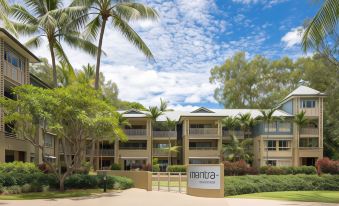 a large apartment building surrounded by trees and grass , with a sign in front of it at Mantra Amphora