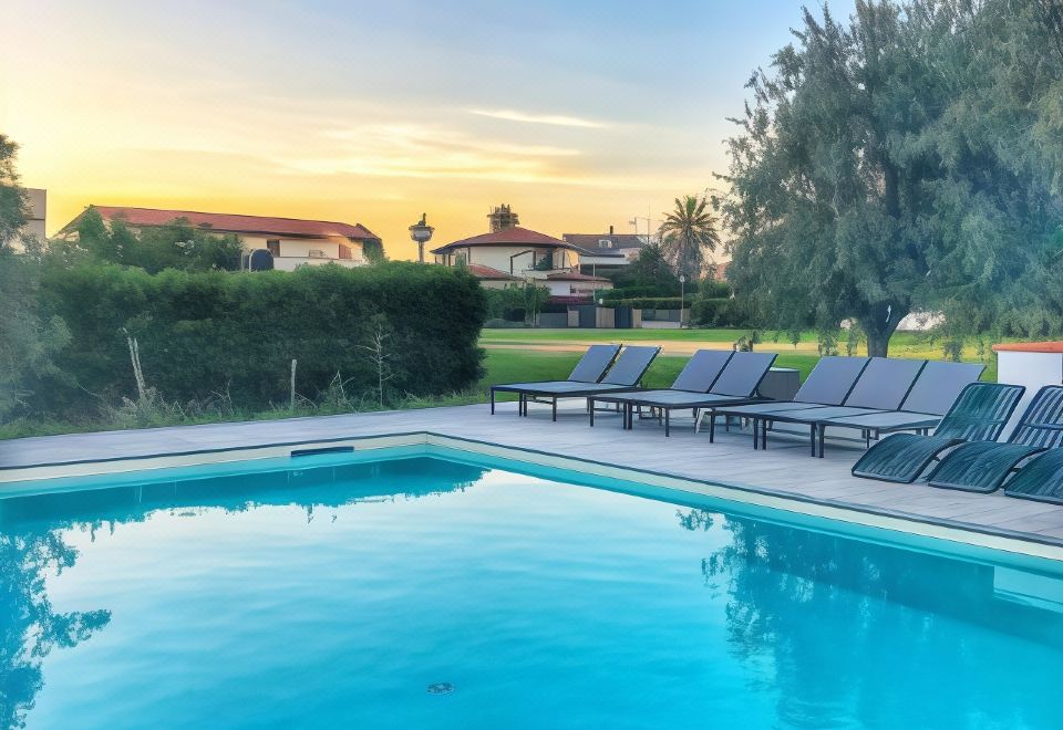 a large swimming pool surrounded by lounge chairs , with a view of the sunset in the background at Smy Civico Zero