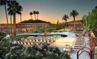 a large swimming pool with lounge chairs is surrounded by palm trees and buildings in the background at Civana Wellness Resort & Spa