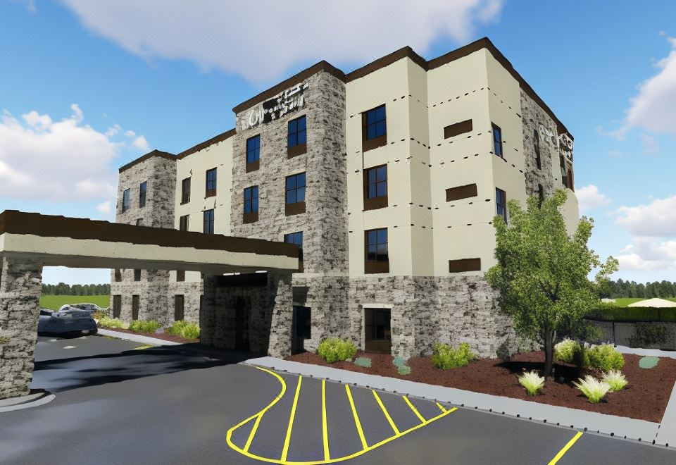 an exterior view of a large , modern hotel building with a parking lot in front at Cobblestone Hotel & Suites - Two Rivers