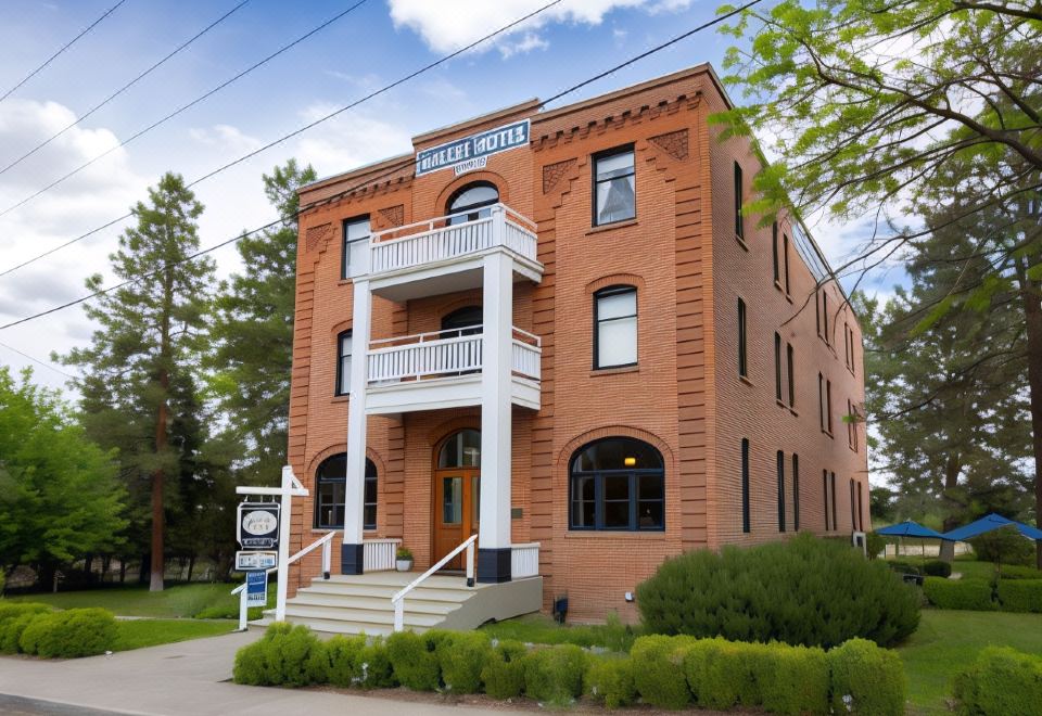 a large brick building with multiple levels and balconies , situated on a street corner near trees at Balch Hotel