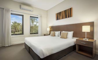 a spacious bedroom with a king - sized bed , large windows , and a painting on the wall at Quest Ipswich