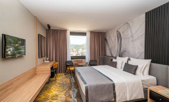 a modern hotel room with a large bed , wooden furniture , and a view of the city at Hotel Holiday