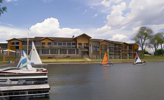 a large building is situated next to a body of water with several boats on the water at King's Pointe Waterpark Resort