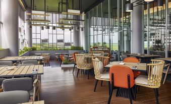 a modern restaurant with wooden floors , large windows , and an open dining area filled with chairs and tables at Front One Boutique Karawang