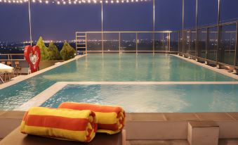 a large swimming pool with a city view , surrounded by colorful towels and white railings at Pakons Prime Hotel