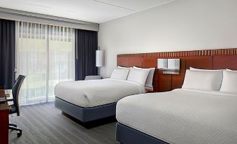 a hotel room with two beds , a window , and a door , all neatly arranged in a clean , modern setting at Courtyard Baltimore Hunt Valley