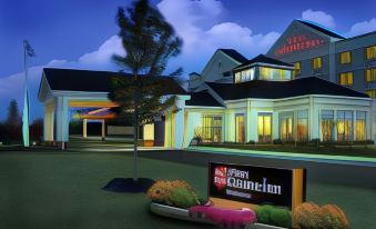 a modern hotel with a large sign in front of it , surrounded by trees and bushes at Hilton Garden Inn Kankakee