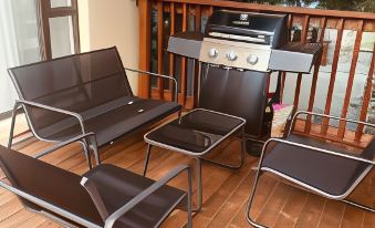 a wooden deck with two black chairs , a dining table , and a grill on it at Sweet Home Alibama