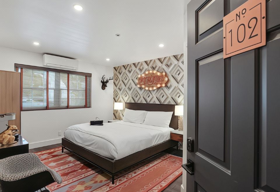 a cozy bedroom with a white bed , a rug on the floor , and a window in the background at The Creekstone