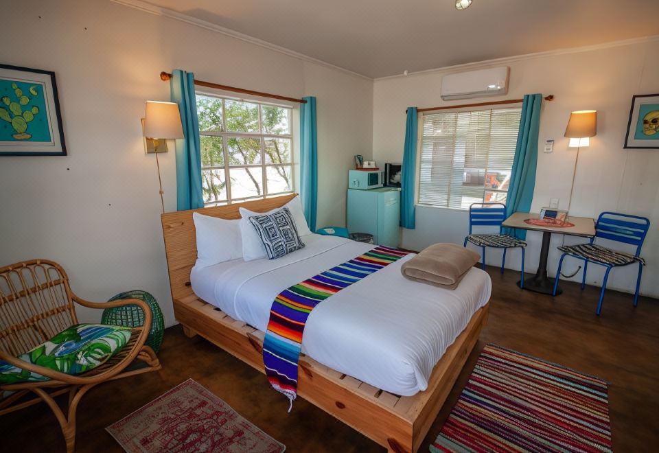 a cozy bedroom with a wooden bed , colorful bedding , and a window view of trees at Antelope Lodge